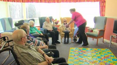 A care home worker talks to residents