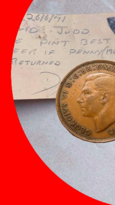 An old penny on top of a piece of card - on it is written: David Judd - one pint of best beer if penny returned