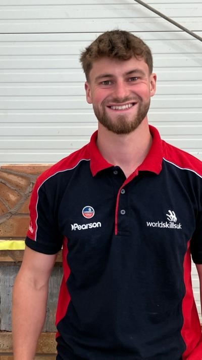A man with brown hair and beard wearing a blue and red polo shirt