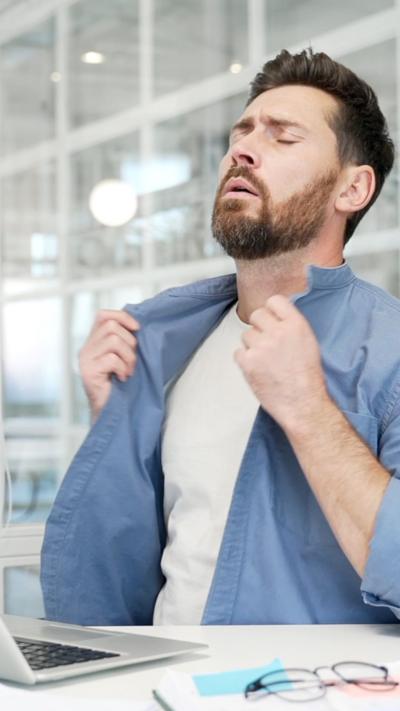 A man looking visibly hot in an office