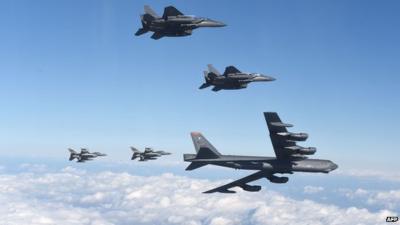 A US B-52 bomber in flight flanked by fighter jets