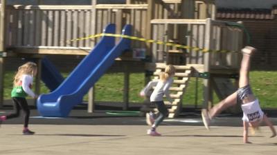 Three children playing outside while remaining distant from each other