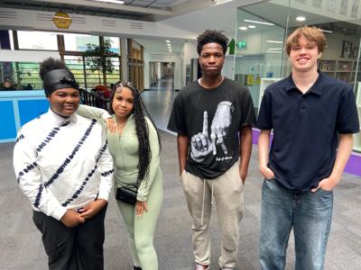 GCSE students stand in a row smiling at the camera