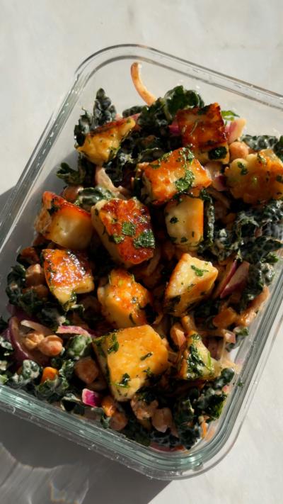 A glass lunchbox filled with cubes of halloumi and veg in a sticky sauce.