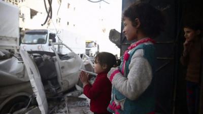 Children applaud as aid trucks arrive