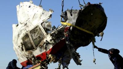 Local workers transport a piece of the Malaysia Airlines flight MH17 wreckage at the site of the plane crash near the village of Hrabove