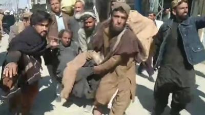 Locals help carry a man caught in blast in Pakistan's Balochistan province