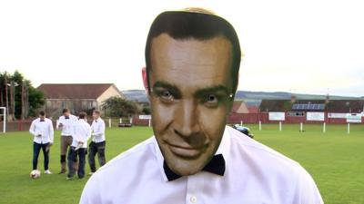 A footballer wearing a Sean Connery mask