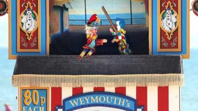 A Punch and Judy puppet show on a beach