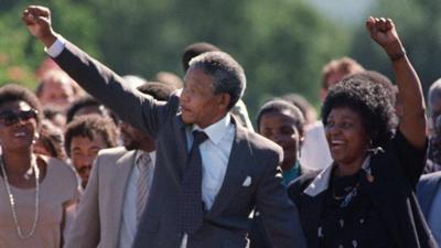 Nelson Mandela and Winnie Mandela raise their arms on his release from prison