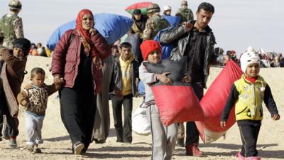 A Syrian refugee family walk with their belongings after crossing into Jordan, near the town of Ruwaished, east of the Jordanian capital Amman, on January 14, 2016.