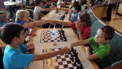 Children shake hands before a chess tournament starts