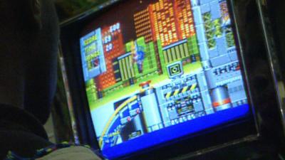 A young person playing a videogame on a screen.