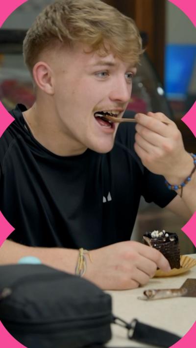 A man eats a slice of cake at a table in a cafe