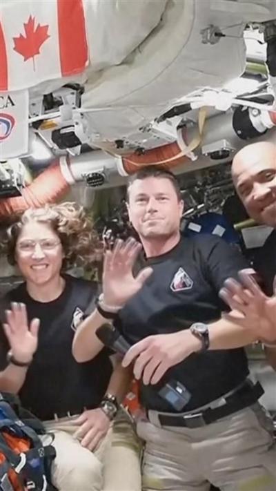 Artemis II crew wave at camera from spacecraft.
