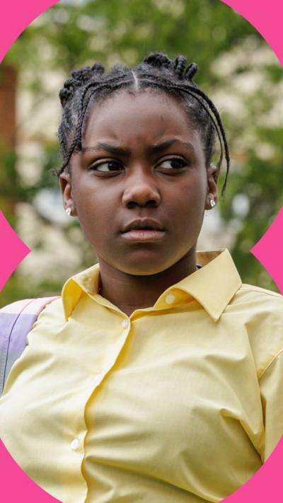 Girl with braided hair who is wearing a yellow shirt.