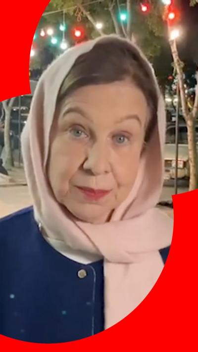 Lyse wears a navy jacket, pink headscarf as she looks into the camera