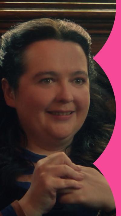 A woman with long brown hair looks awkward while holding her hands together