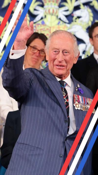 King Charles looks at the camera while giving a speech from behind a lectern on a stage.