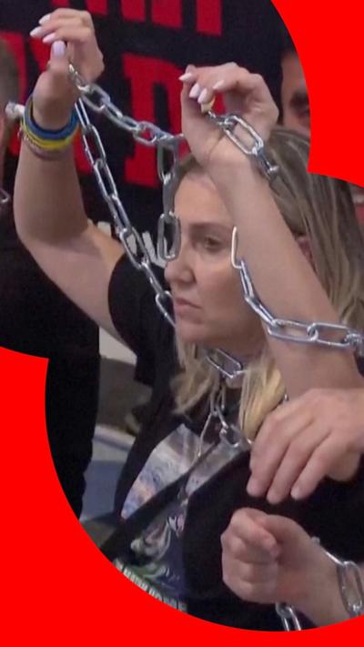 A protester wrapped in chains holds her arms in the air