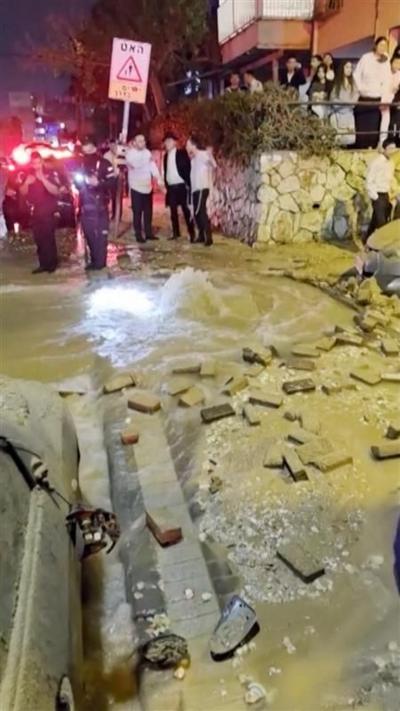 Water splashing up out of a cracked street in Israel. Bricks are scattered