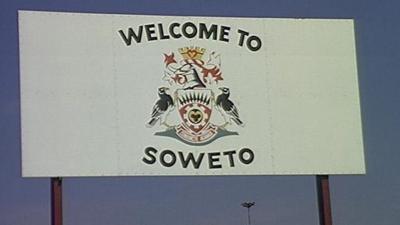 A sign that says 'Welcome to Soweto' with the township's crest on a white background.