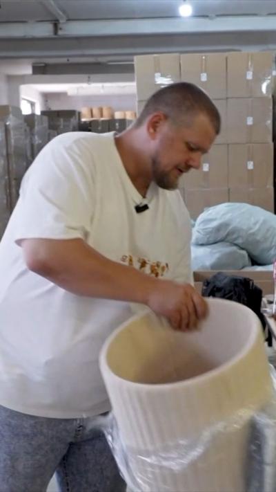Dmitri unwraps cream-coloured cylinder shaped item of furniture