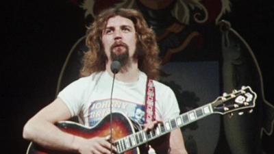 Billy Connolly on stage with a guitar