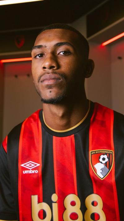 A close up of Rayan looking at the camera wearing a red and white striped Cherries kit