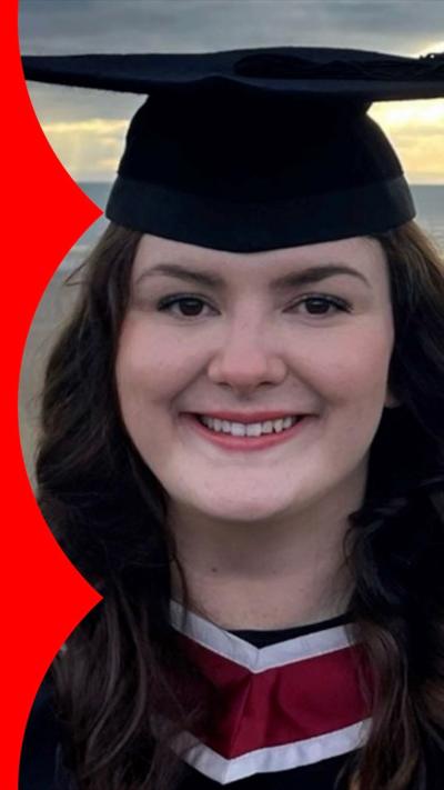 Caitlin in her graduation gown on a beach