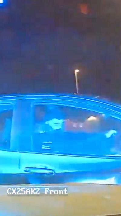 Grainy footage from a dashcam of a man behind the wheel of a car, side on to the camera