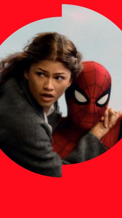 Spider-Man carries a person through a city, with buildings blurred in the background.