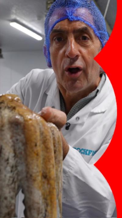 Man in hairnet and white coat holding up an octopus