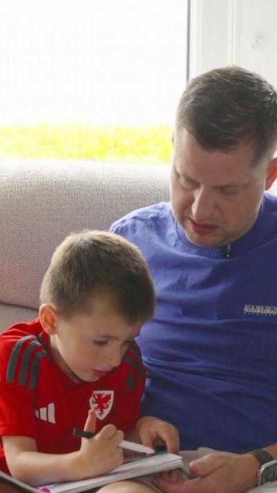 Man in blue t-shirt with his son in a red Wales t-shirt. 