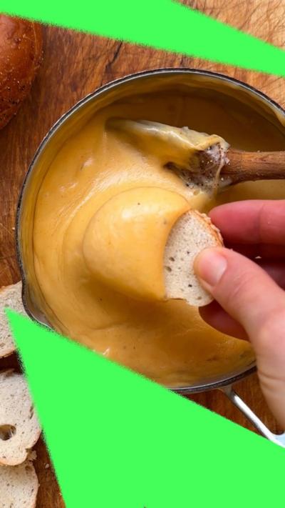 A piece of bread dipped into the beer cheese dip