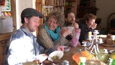 Group of people sit around a kitchen table eating soup and sourdough.