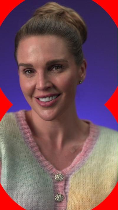Danielle Lloyd smiles wearing a multicoloured cardigan; she has brown hair tied in a bun