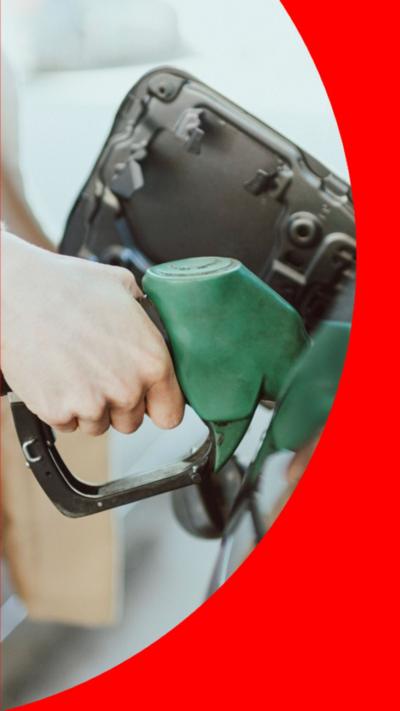 A woman's hand putting fuel in her car using a green fuel pump.