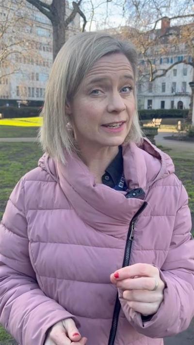 BBC presenter wearing a pink coat and holding a microphone while standing outside