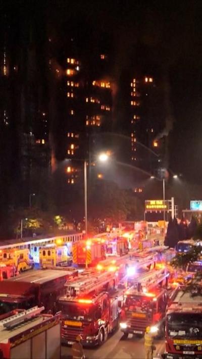 Bright lights and fire engines can be seen in front of a burning apartment block.