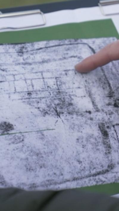 A finger pointing at a greyscale map of a Roman villa
