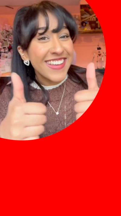 A young student smiling and giving a thumbs up