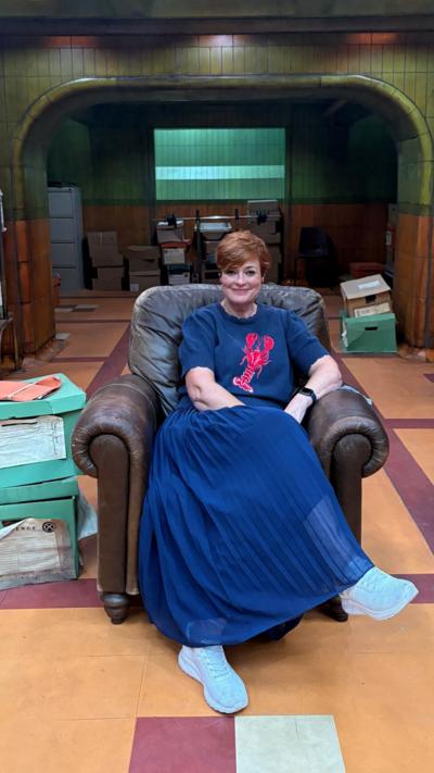 Woman with blue skirt and auburn short hair smiling