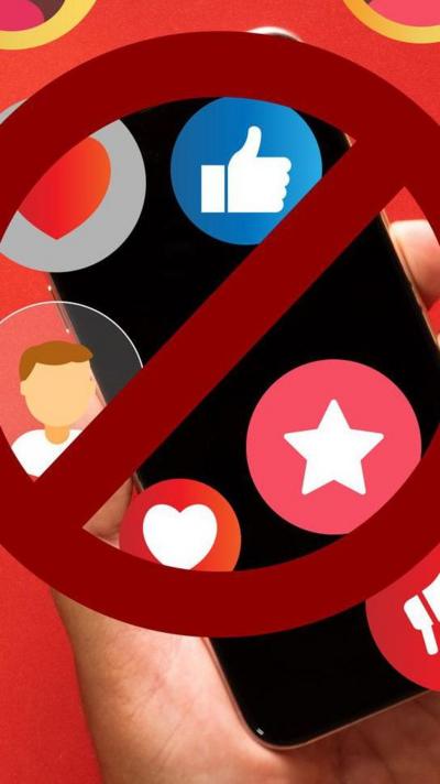 Emojis float over a smartphone, held by a hand against a red background. A stop sign is slapped over the top of the image.