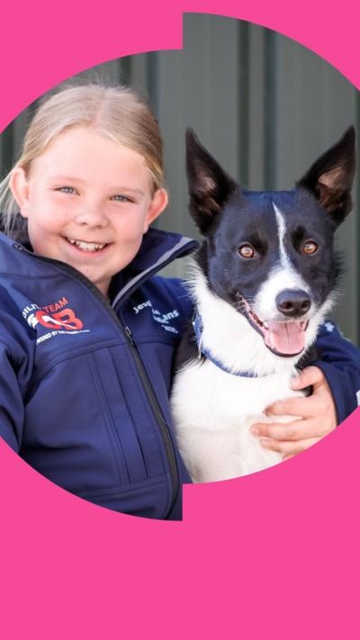 A girl, Jess, in a blue Team GB jacket smiles and holds her dog Micky