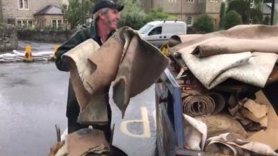 Person throwing a carpet into a skip