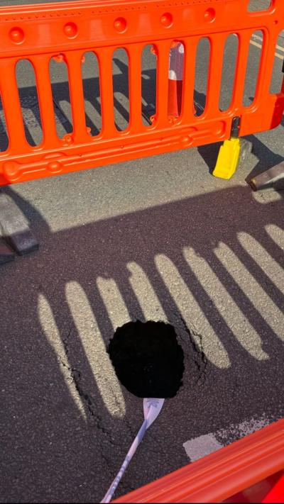A small sinkhole surrounded by orange barriers
