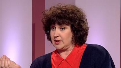 Jenni Murray being interviewing in studio, wearing a red blouse and navy cardigan.