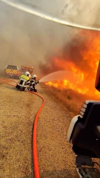 View from camera glasses of three firefighters trying to put out a fire with a hose