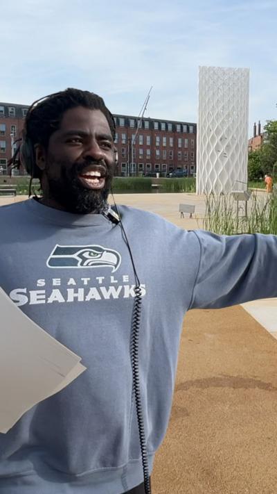 A man wearing headphones and a grey Seattle Seahawks jumper.